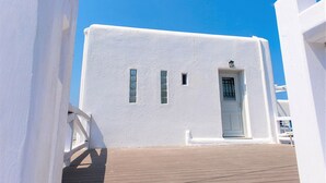 Un edificio blanco con puerta y ventanas, un muelle de madera y un cielo azul despejado.
