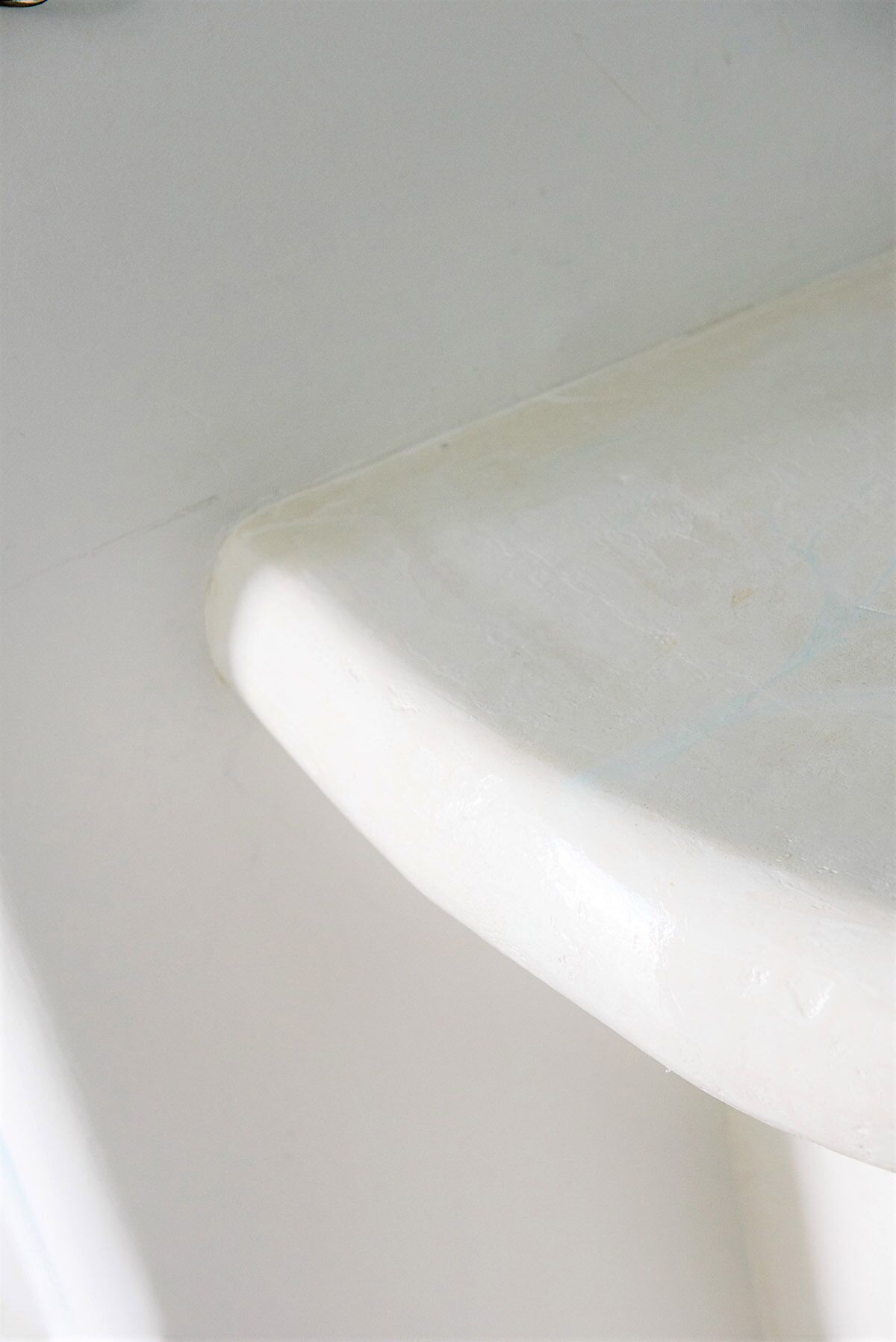 Primer plano de una superficie blanca y curvada, probablemente parte de un accesorio de baño.
