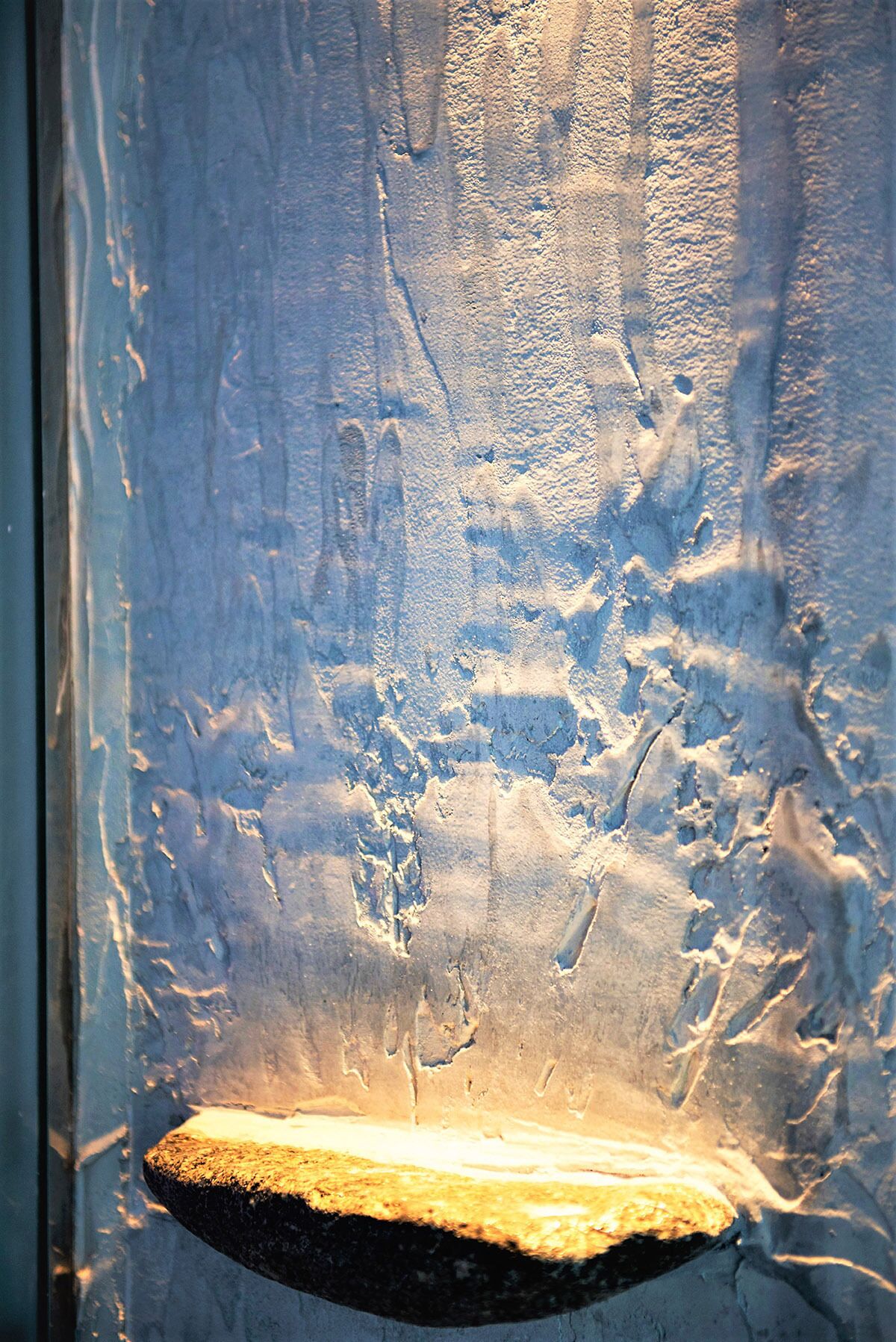 Una ventana con un diseño de vidrio esmerilado y un alféizar de piedra en la parte inferior.