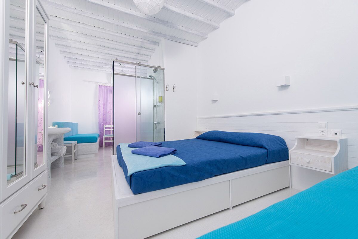 Un dormitorio moderno con una cama grande, una mesita de noche, un armario y una cabina de ducha de vidrio.