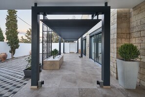 A covered outdoor area with a pergola, potted plants, and a tiled floor. - Sia Mare Residence (Rhodes)