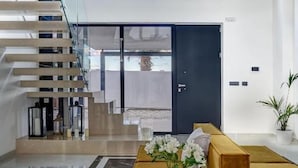 Ein modernes Interieur mit Treppe, einer Chandelierleuchtre, einem Sofa und einem Tisch mit Blumen.