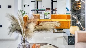 Ein modernes Wohnzimmer mit einem runden Couchtisch, einer Couch und einem Essbereich im Hintergrund.