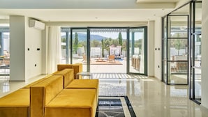 Ein modernes Interieur mit einer Couch, einer Glastür zu einem Außenbereich mit Pool und Möbeln.