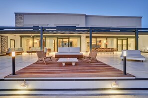 An outdoor patio with a wooden deck, seating area, and modern furniture. - Sia Mare Residence (Rhodes)