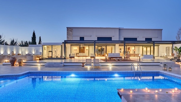 Ein moderner Poolbereich mit rechteckigem Pool, Liegestühlen und einer gut beleuchteten Außenlounge.
