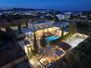 A modern residential building with a swimming pool, outdoor seating, and a view of the sea. - Sia Mare Residence (Rhodes)