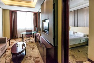 Una habitación de hotel con cama, televisión, escritorio y silla.