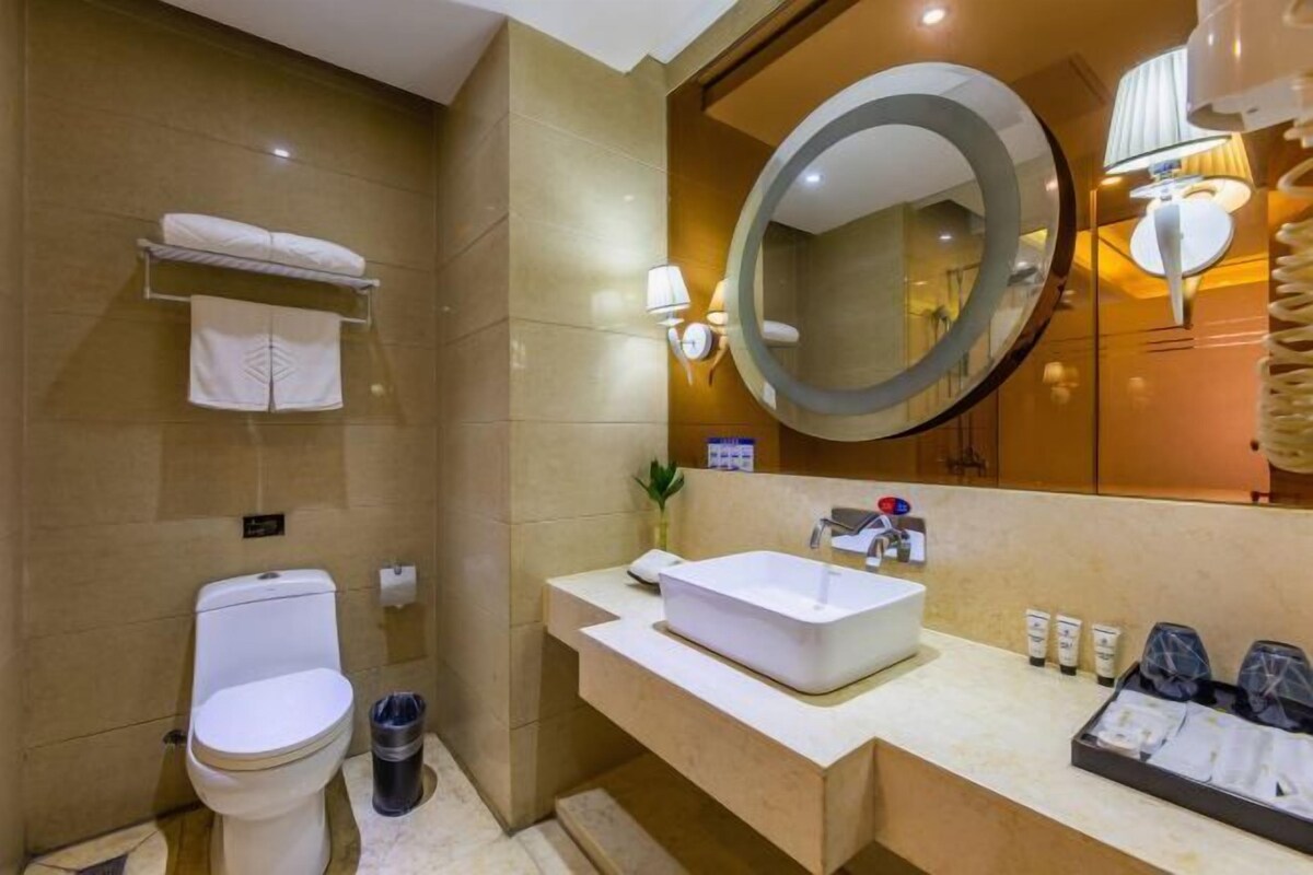 A modern bathroom with a toilet, sink, mirror, and towel rack.