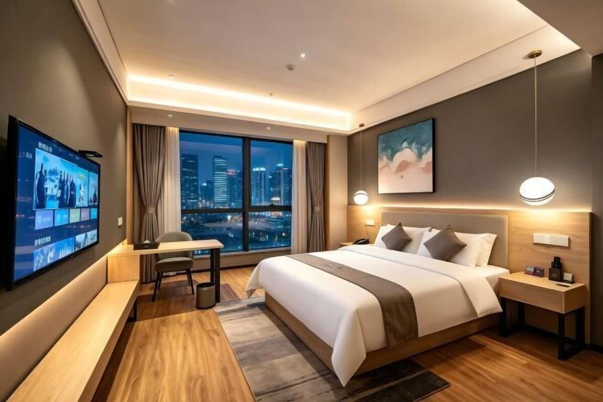Une chambre d’hôtel moderne avec un grand lit, un bureau, une télévision et une vue sur la ville.