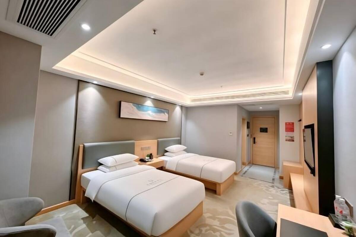 Une chambre d’hôtel avec deux lits, un bureau, une chaise et un téléviseur.