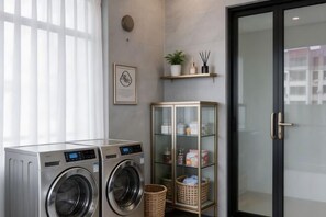 A laundry area with two washing machines, a glass cabinet with toiletries, and a door with a reflection.
