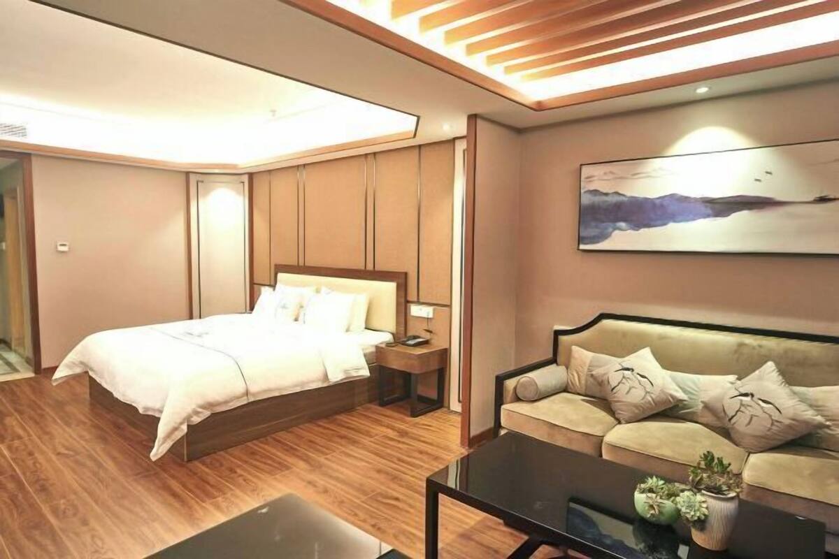 Une chambre d’hôtel moderne, équipée d’un lit, d’un canapé, d’une table basse et d’un tableau au mur.