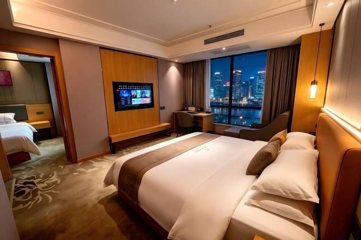 Une chambre d’hôtel avec un grand lit, une télévision, un bureau et une vue sur le paysage urbain.