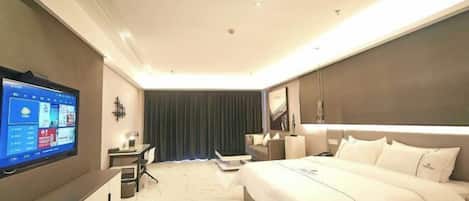 Une chambre d’hôtel moderne dotée d’un grand lit, d’un bureau avec un ordinateur, d’une télévision à écran plat et d’une grande fenêtre avec des rideaux.