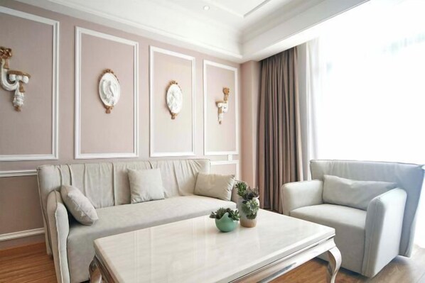 A modern living room with a sofa, armchair, and a coffee table with decorative plants. - Youyi Holiday Hotel (Foshan Lishui Jiaxuan Shopping Plaza Branch) (Foshan)