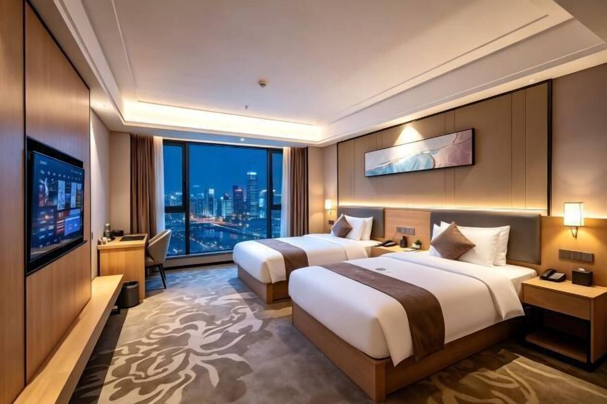 Une chambre d’hôtel avec deux lits, un bureau, une télévision et une vue sur la ville.