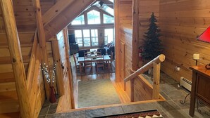 Ein Holzblockhaus-Interieur mit Essbereich, einem Weihnachtsbaum und einer Treppe, die zu einer Schlafloge führt.