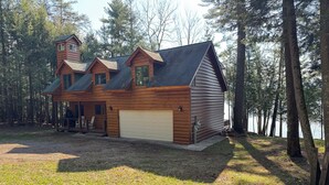 Eine Holzhütte mit Garage, umgeben von Bäumen und einem See.