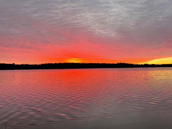 A calm lake at sunset with a silhouette of trees in the background. - Lakefront Hemlock house on 3 acres, 5-Bdrm retreat on private lake, near casino (Minocqua)