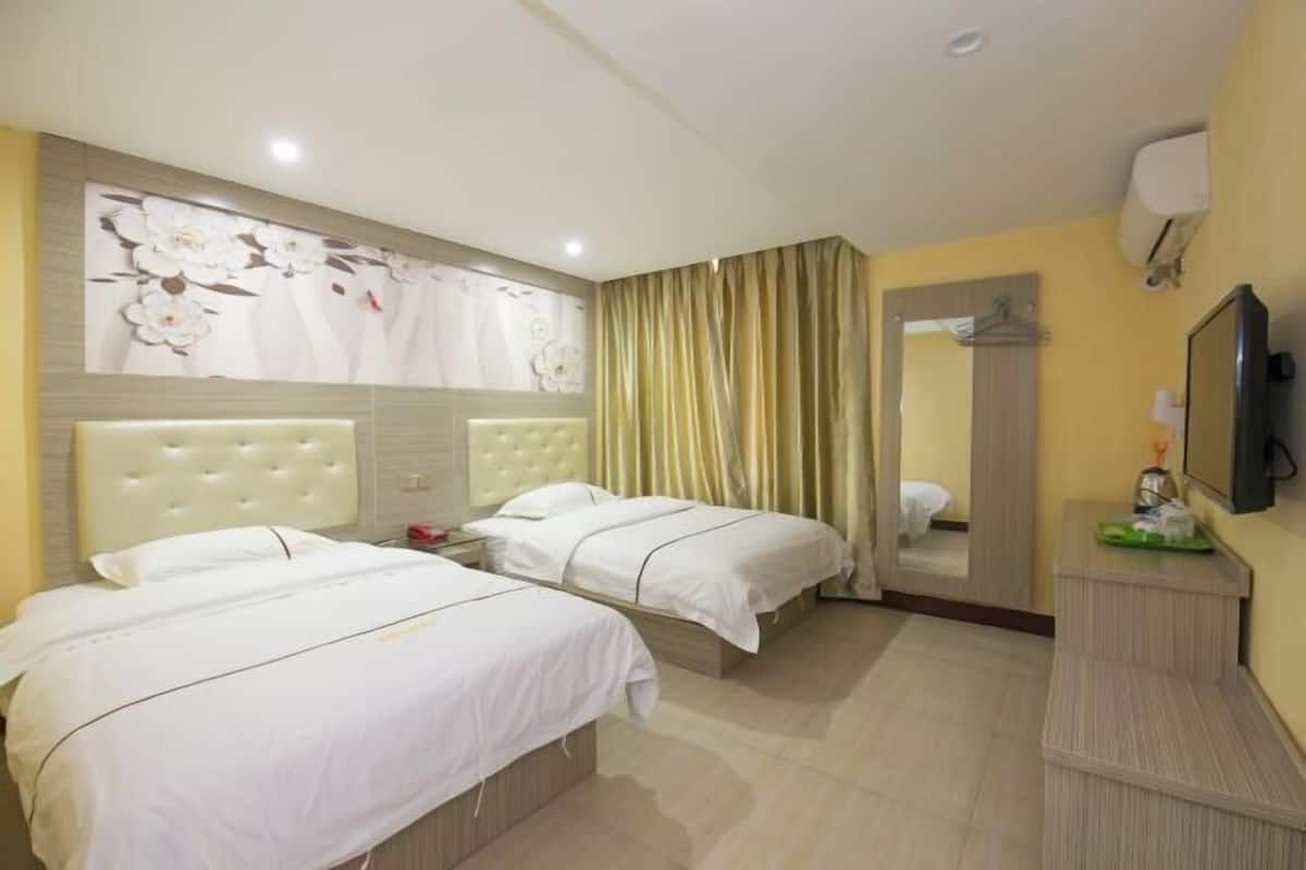 A hotel room with two beds, a large mirror, a flat-screen TV, and a wall-mounted air conditioner.
