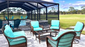 A covered outdoor seating area with wicker furniture and a pool. - Stunning Sunsets-Heated Pool and Spa-Golf Course Views (Cape Coral)