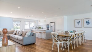A modern kitchen with white cabinets, a central island, and pendant lighting. - Salt and Light Mollymook (Mollymook Beach)