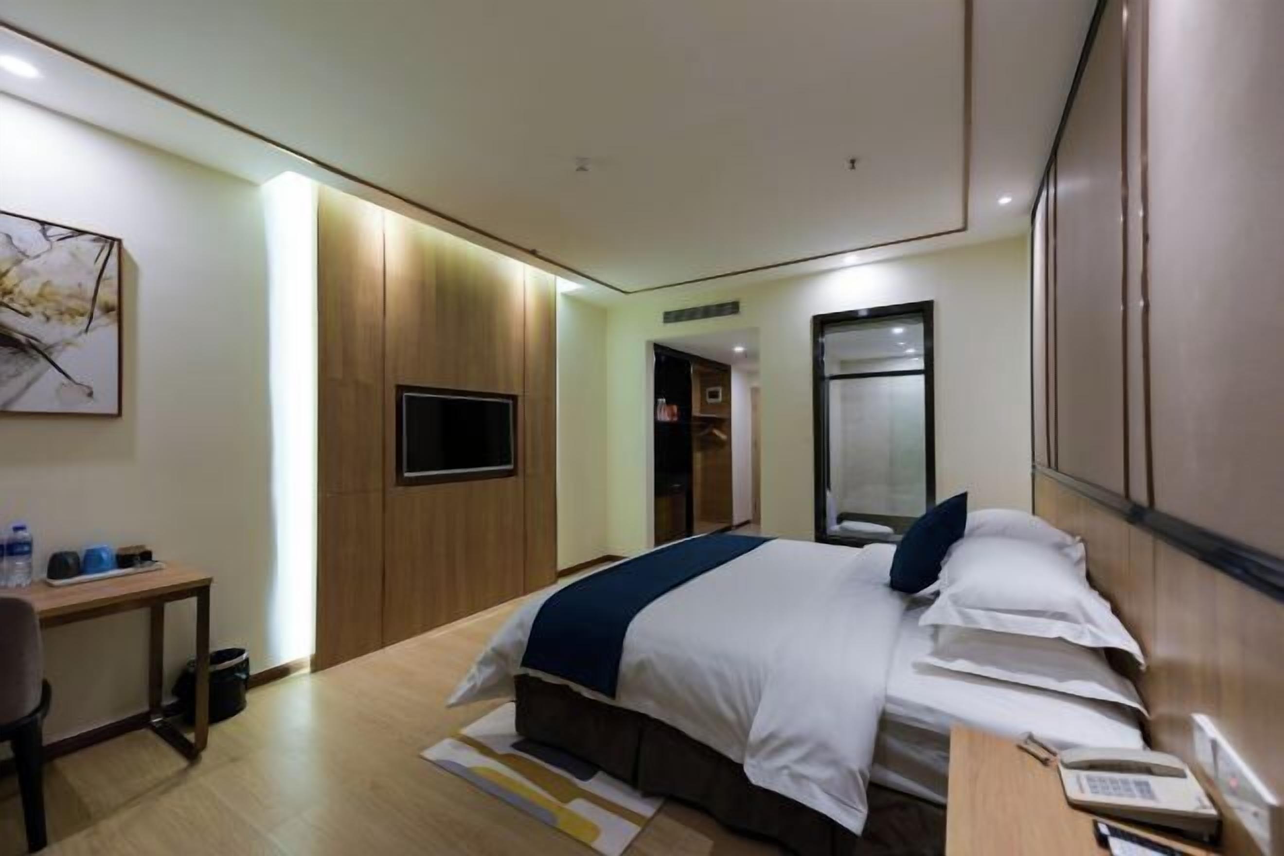 Une chambre d’hôtel comprenant un lit, une table de chevet et un bureau avec une chaise.