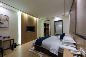 A hotel room with a bed, bedside table, and a desk with a chair. - Tomato Hotel (Dongguan)