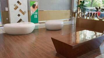 A reception area with a wooden floor, a reception desk, and two white seating areas.