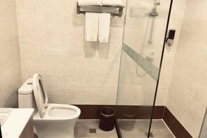 Un baño moderno con inodoro, ducha y cabina de ducha con mampara de vidrio.