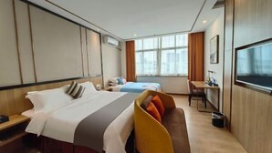 A hotel room with a bed, a sofa, a desk, a TV, and a window. - Tomato Hotel (Dongguan)