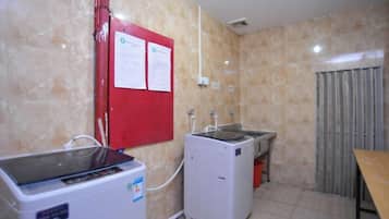 Quarto com máquina de lavar, secadora, pia e um mural vermelho.