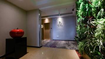 A hallway with a red apple sculpture, a wall with a number sign, and a vertical garden.