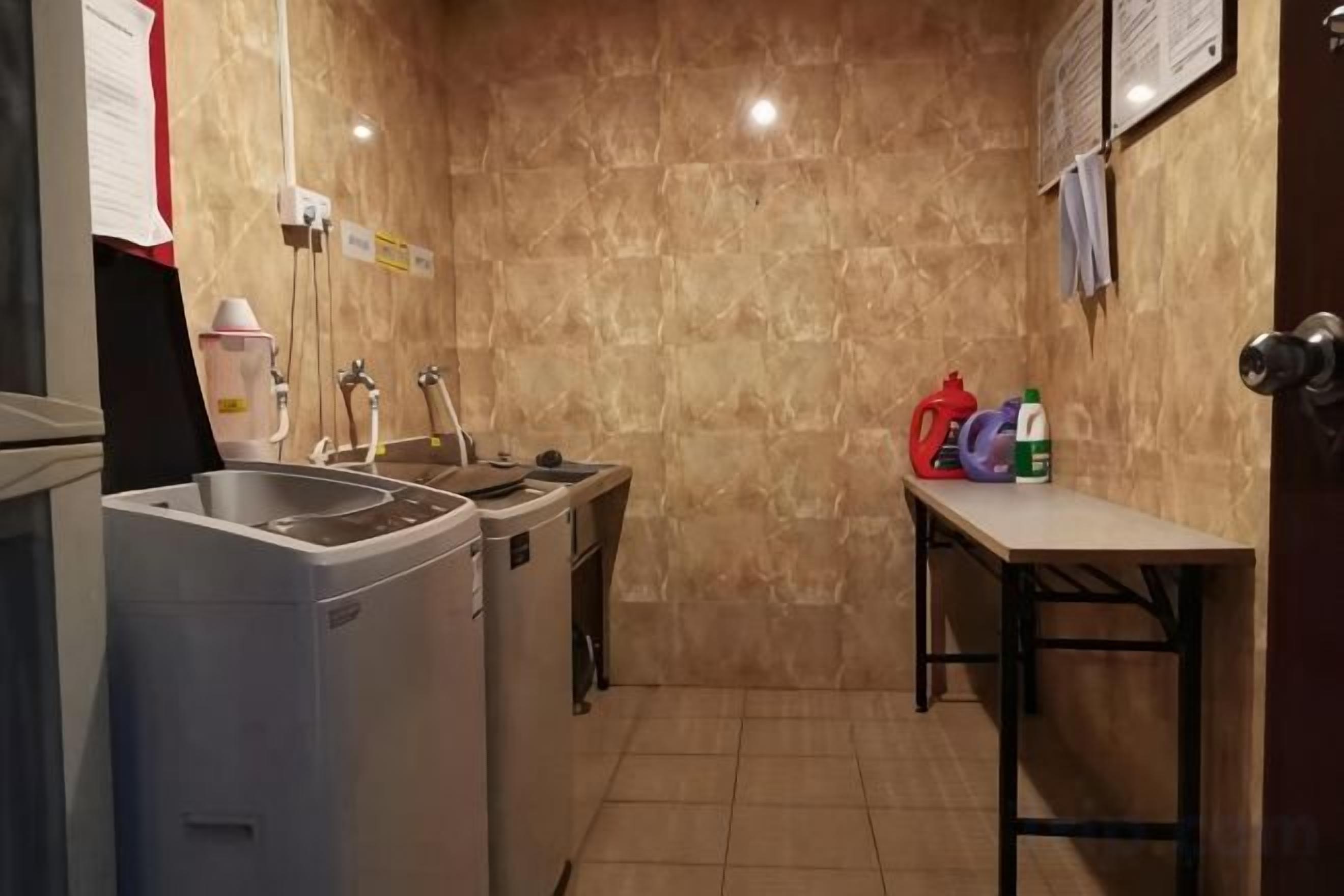 A compact kitchen with a sink, two dishwashers, a table, and a wall-mounted mirror.