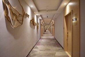 A hotel corridor with doors, a patterned floor, and wall art. - Tomato Hotel (Dongguan)