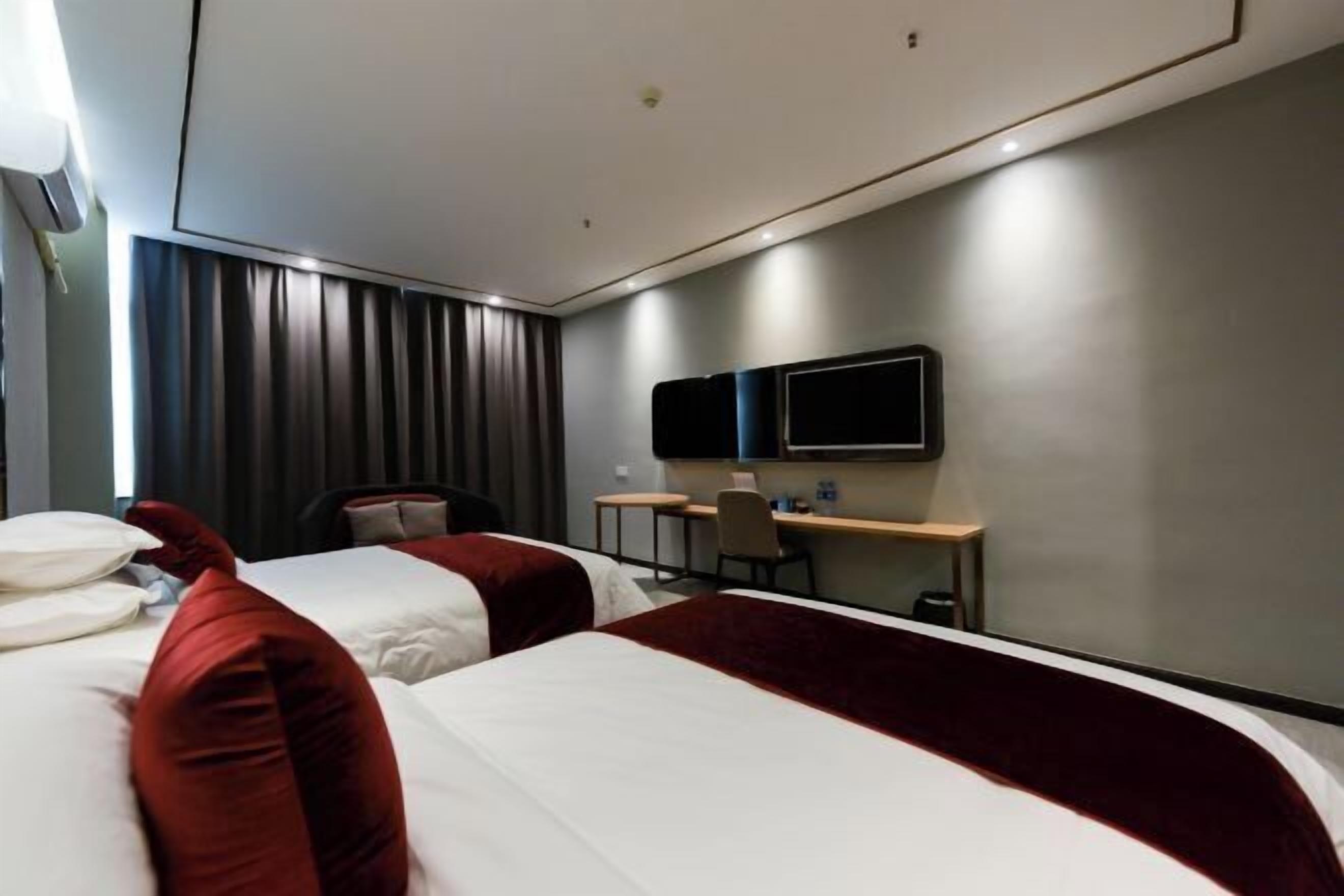 Habitación de hotel con dos camas, un escritorio, una silla y un televisor de pantalla plana.