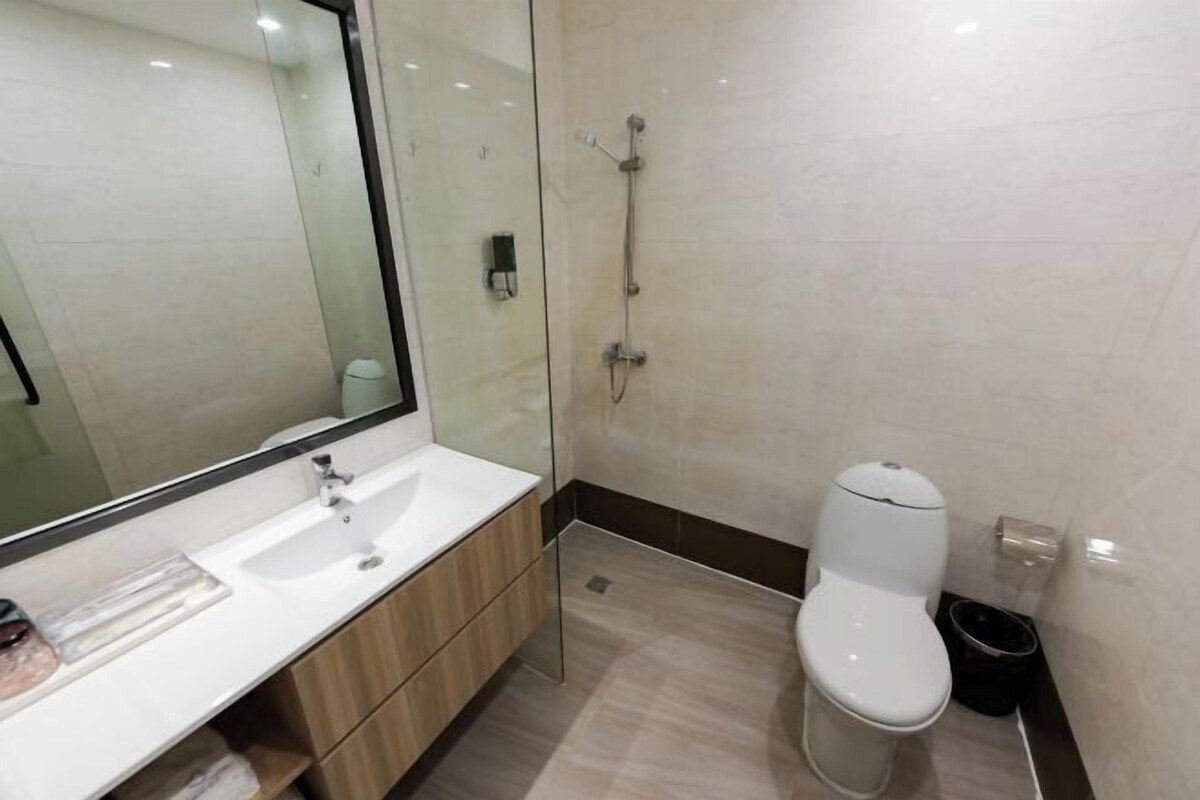 Un baño moderno con cabina de ducha de vidrio, inodoro blanco y tocador de madera con espejo.