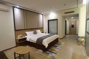 Una habitación de hotel con cama, mesita de noche y una pequeña mesa redonda.