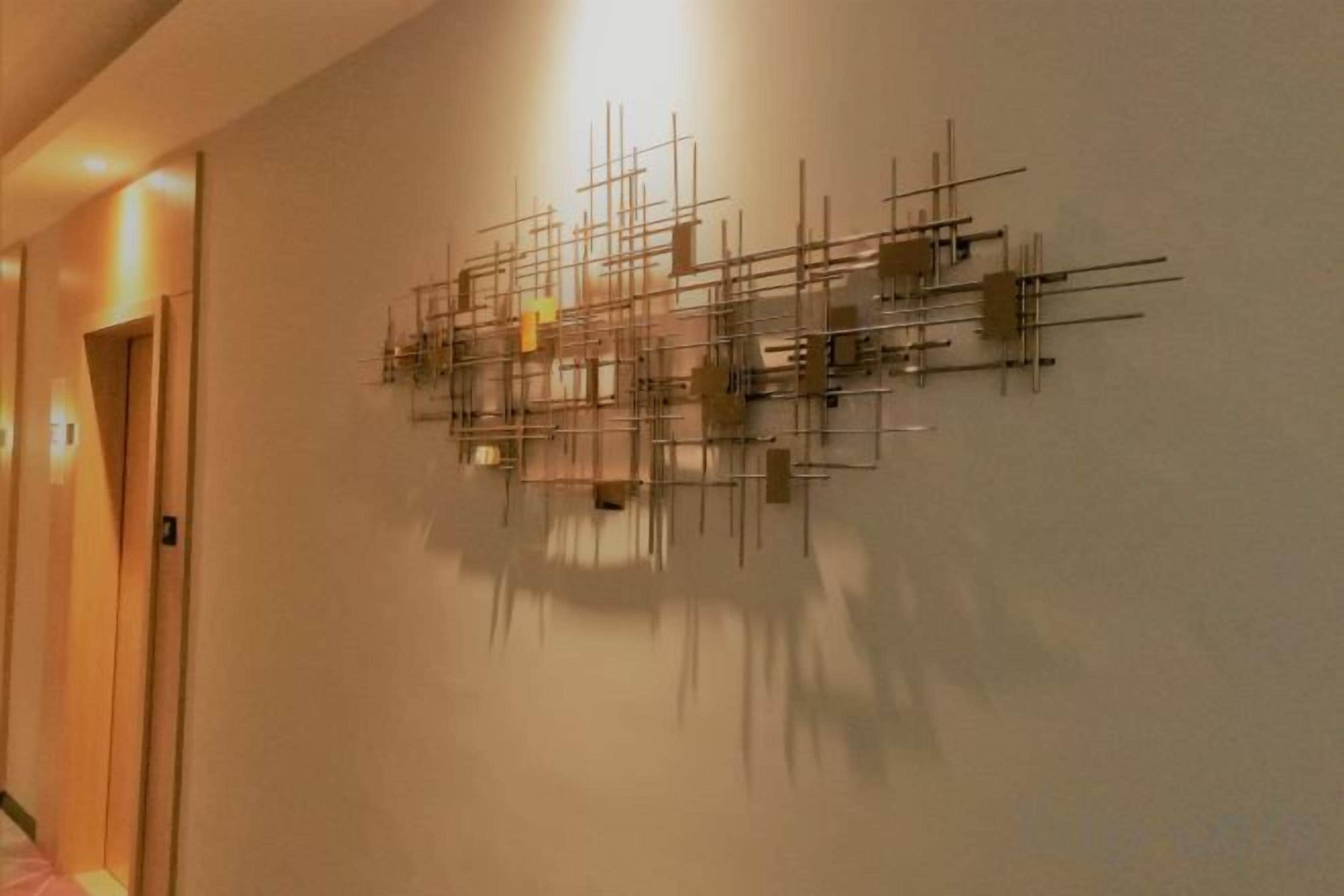 Parede com uma escultura metálica geométrica.