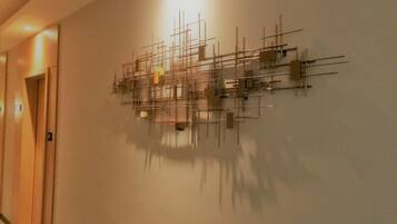 Parede com uma escultura metálica geométrica.