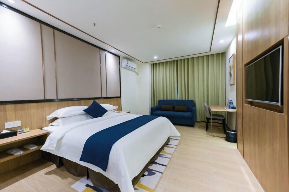 Una habitación de hotel con cama, mesita de noche, escritorio, silla y televisión.
