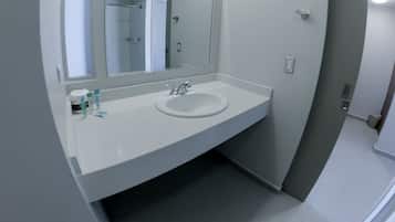 A bathroom with a white sink, a mirror, and a shower door.