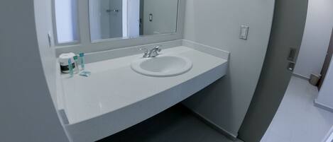 A bathroom with a white sink, a mirror, and a shower door.
