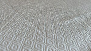 A bed with a patterned white bedspread and a wooden headboard. - Royal Delonix Hotel (Penuelas)