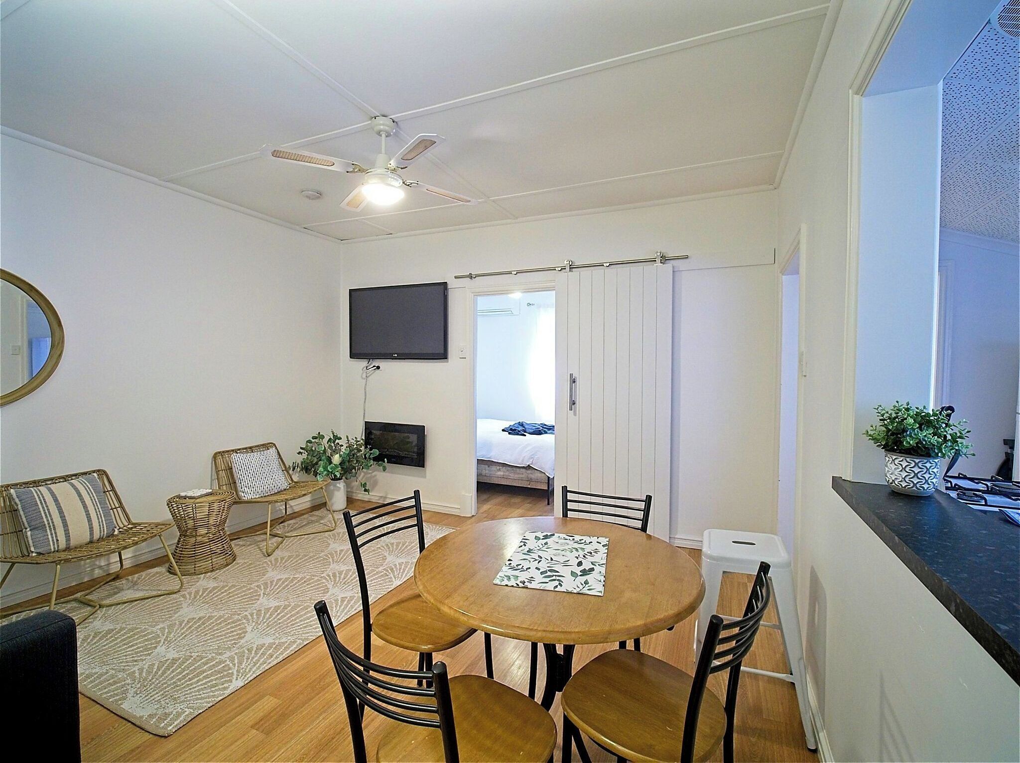 A compact living space with a dining area, a TV, and a bed in the background.
