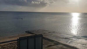 A beach view with a clear sky, calm sea, and a sun reflecting on the water. - Sea Salt Apartment 3 - Short walk to beach! Free WiFi! newly decorated! (Stansbury)
