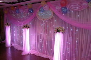 Un escenario con cortinas decoradas y arreglos florales.