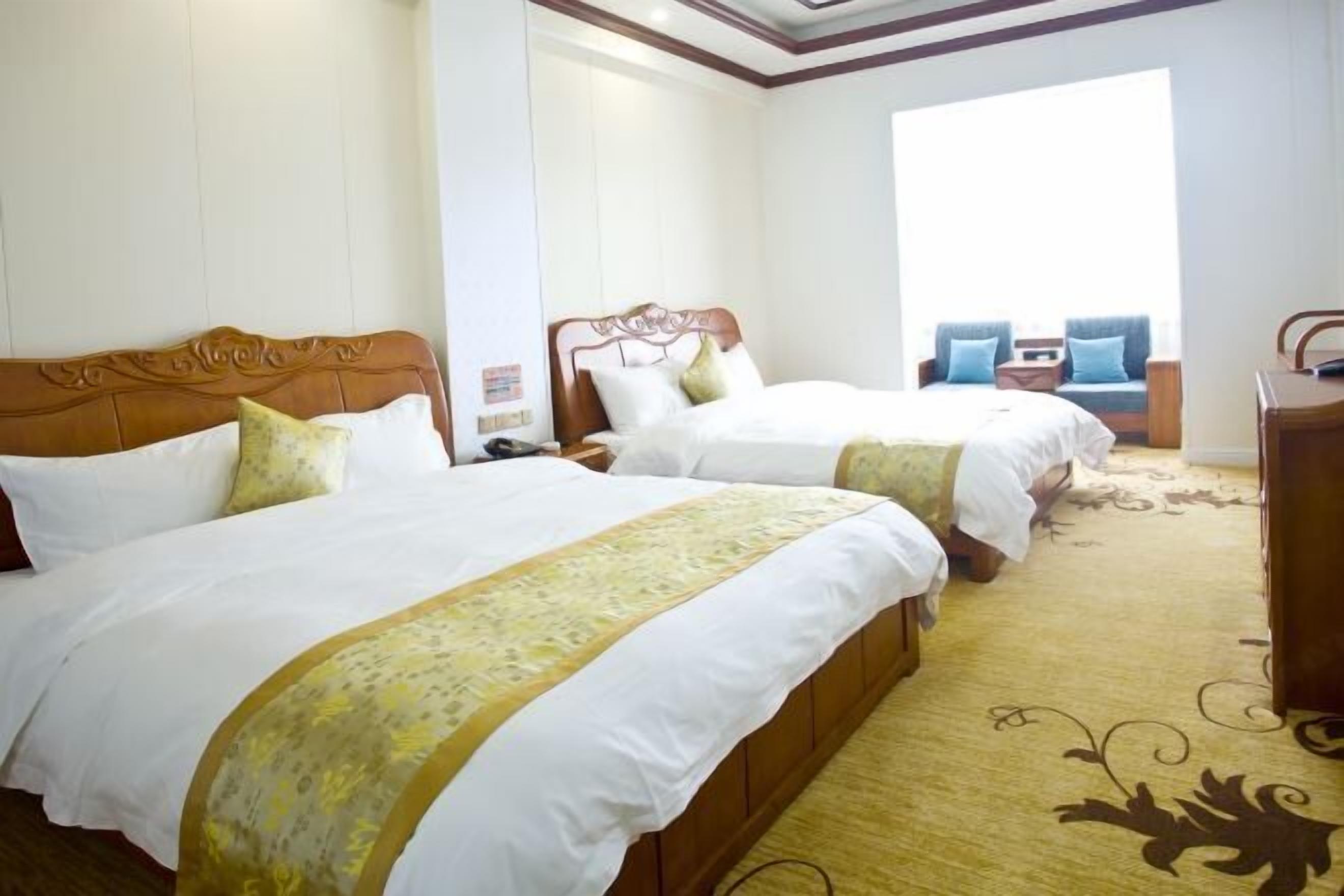 A hotel room with two beds, a large window, and a view of the outdoors.