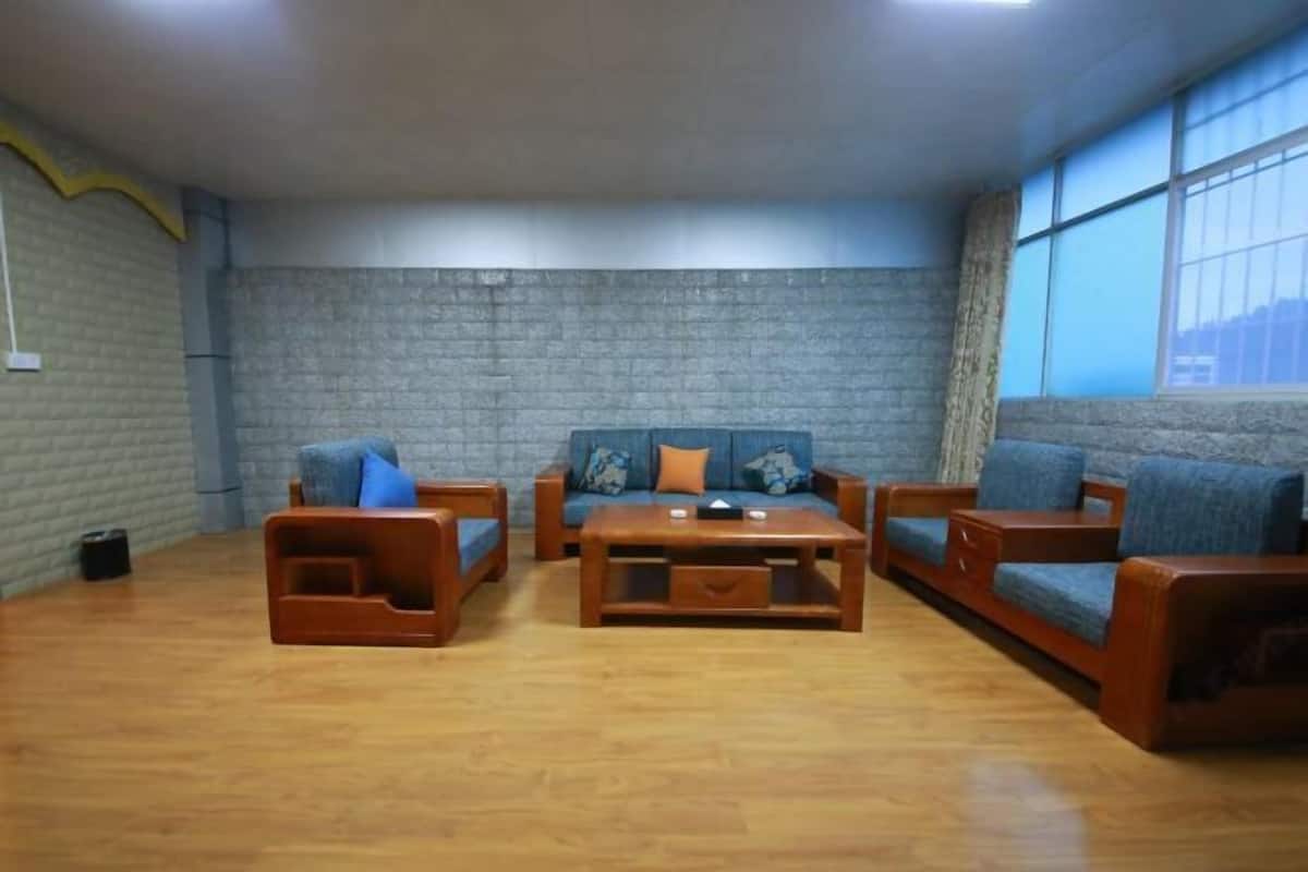 A living room with a brick wall, wooden furniture, and large windows.